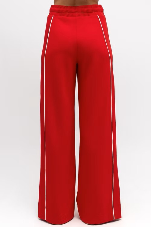 Model wearing vibrant red wide leg pants with elastic waistband, styled with a fitted white tank.