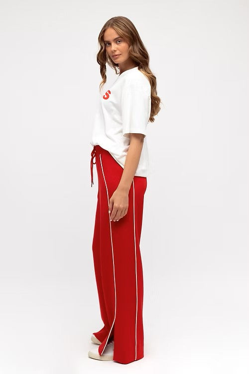 Model wearing vibrant red wide leg pants with elastic waistband, styled with a fitted white tank.
