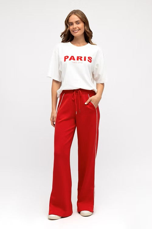 Model wearing vibrant red wide leg pants with elastic waistband, styled with a fitted white tank.