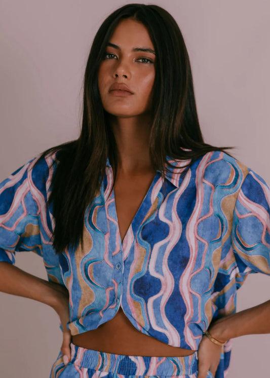 Model wearing Corfu Shirt in Greece Print Blue with boxy fit, short cuffed sleeves, button-through front and scooped hemline