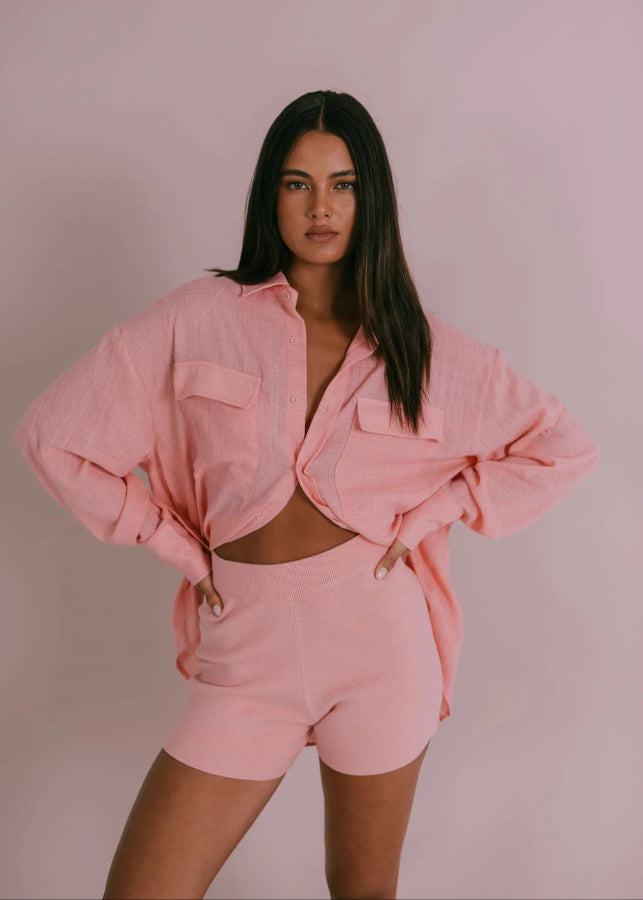 Model wearing fitted high-waisted ribbed knit shorts in pinky peach with elastic waistband from Vivian The Store