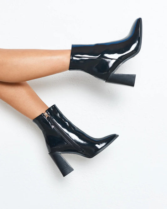 lady wearing ankle boots with an invisible zipper made from black patent faux leather and a mid block heel